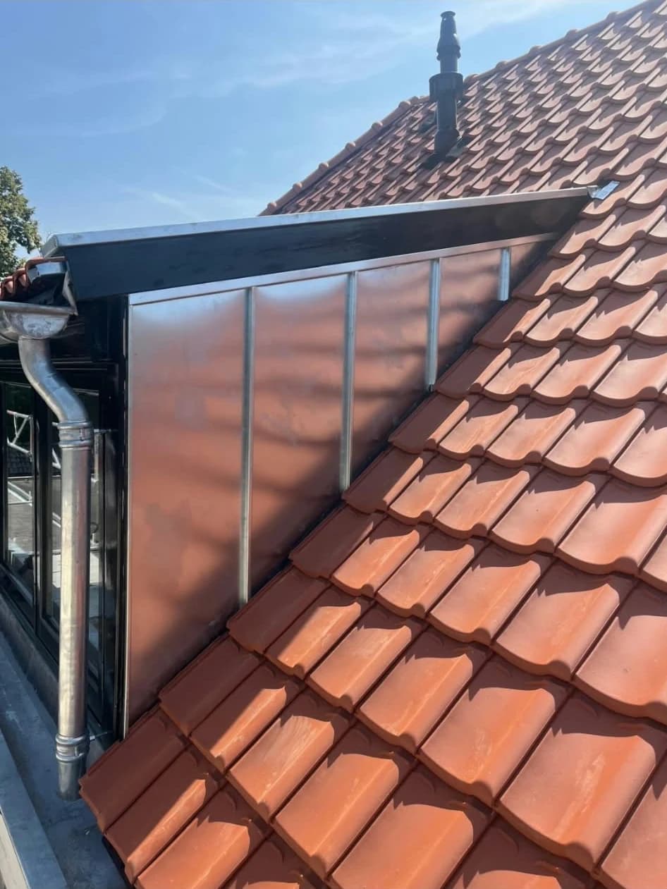 Detail van een pannendak met zinken dakkapel en dakgoot